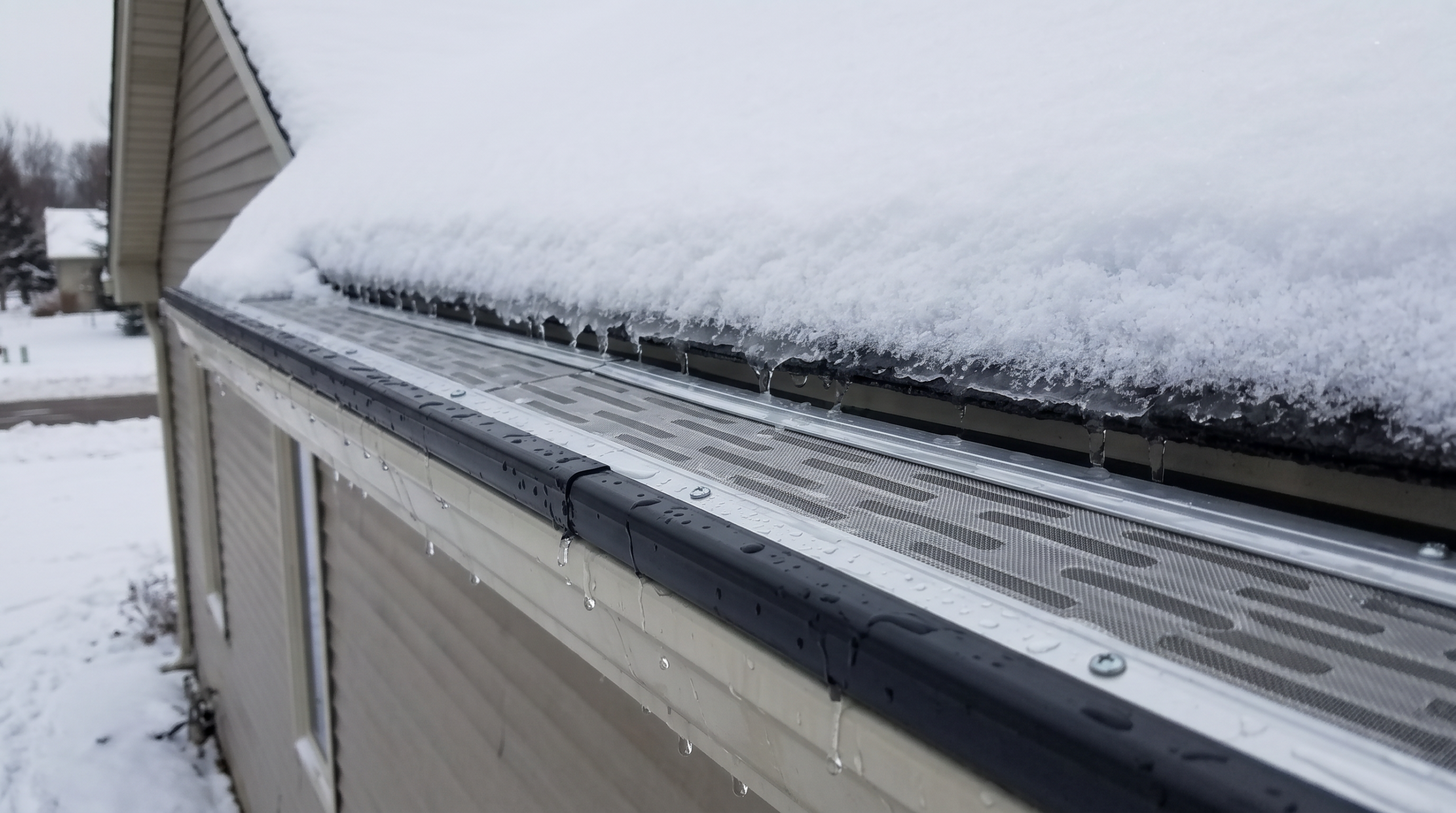 Gutter guard with micro-mesh cover under heavy snow load on residential roof edge