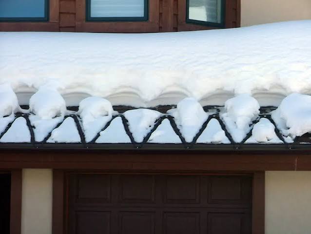 Heat cable installed along snow-covered roof eave and gutter in winter