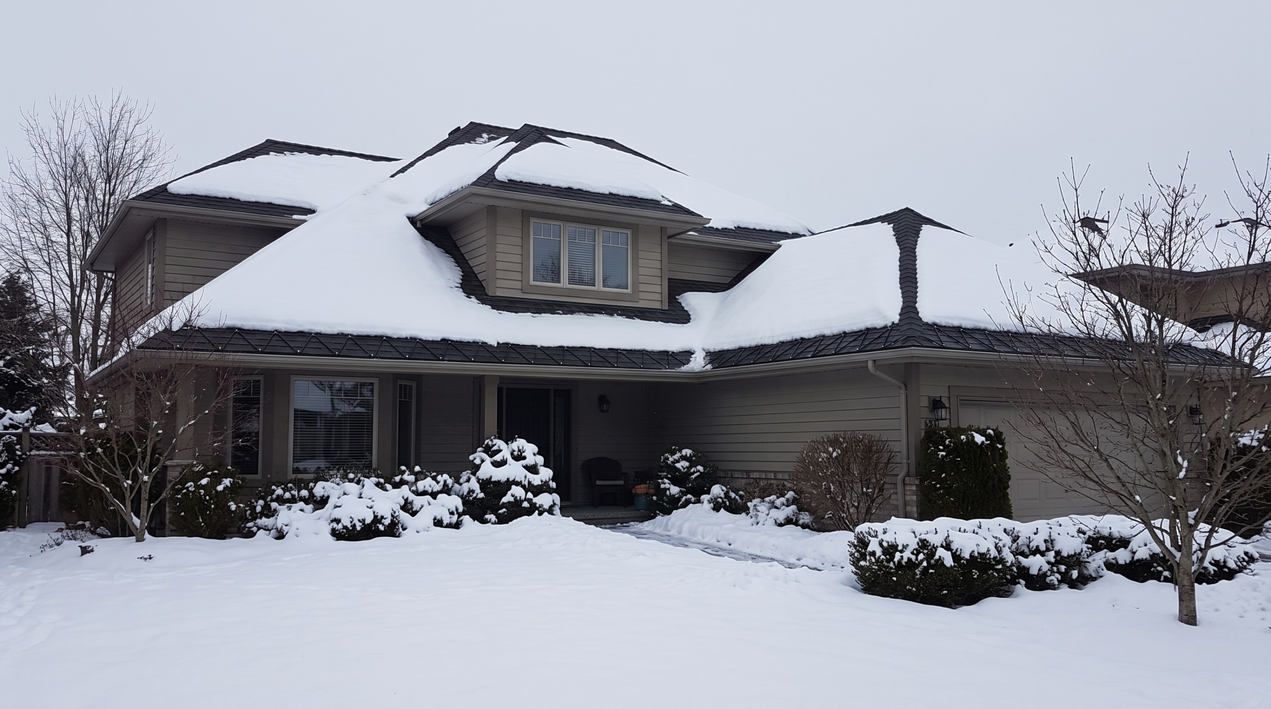 Snow-covered home with clean ice-dam-free roof edges and dormer in winter