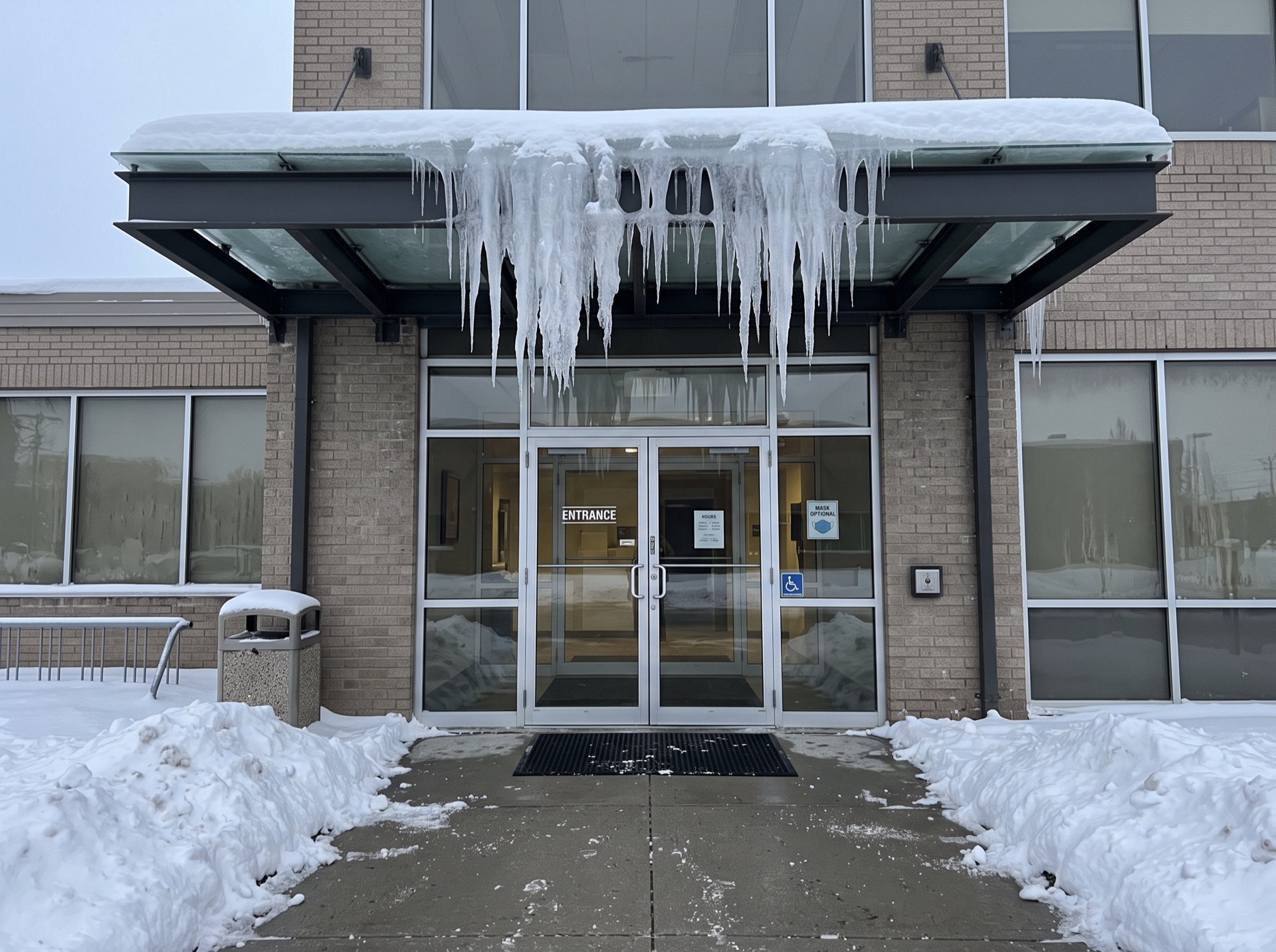 Large icicles hanging from commercial building entrance canopy in winter
