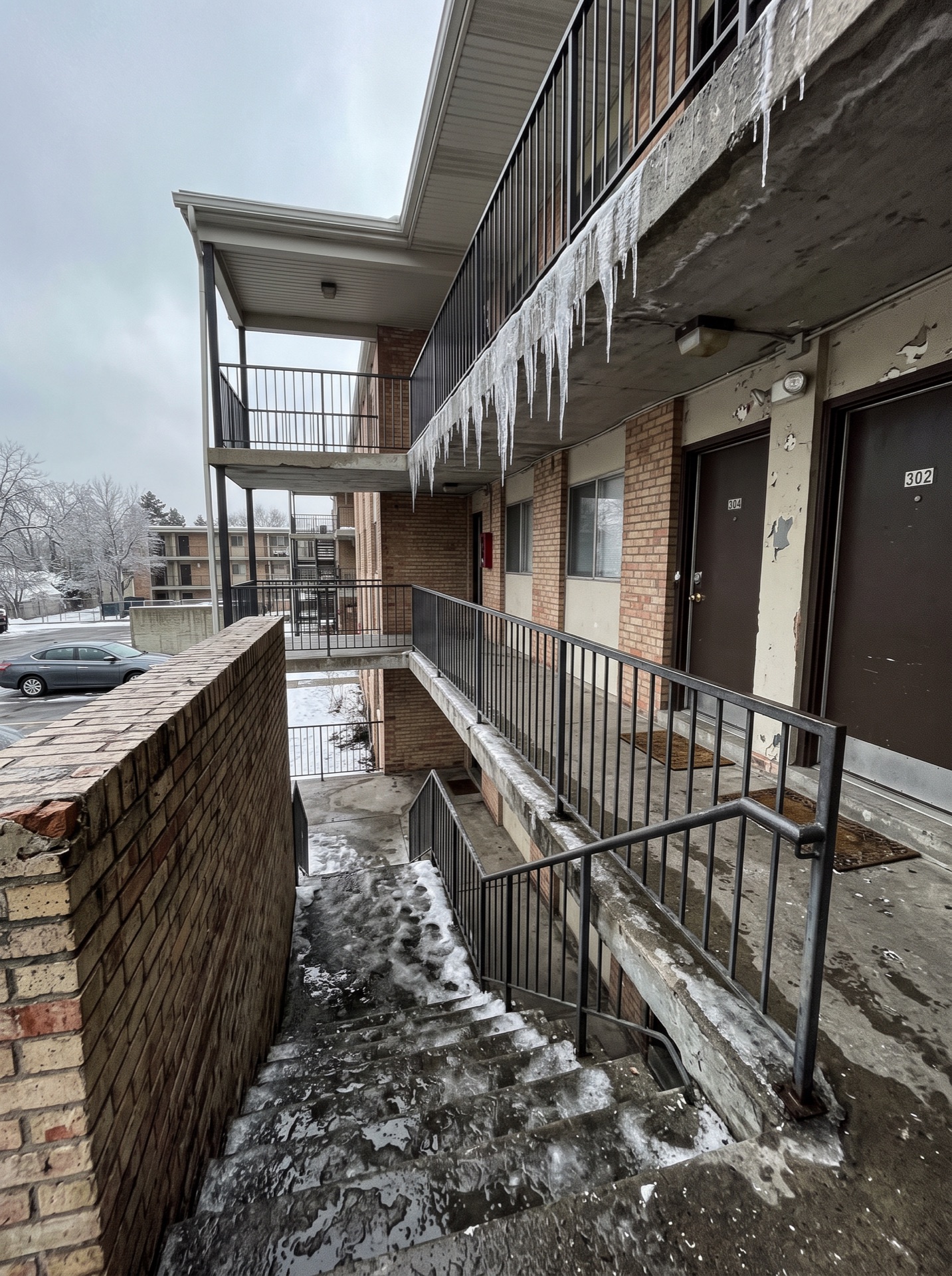 Icicles hanging from apartment breezeway walkway above icy stairs in winter