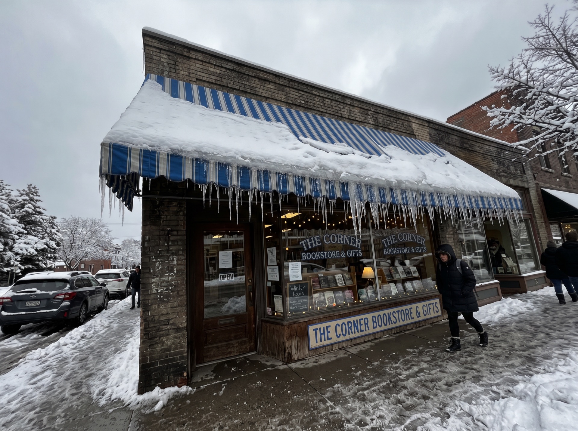 The Corner Bookstore and Gifts storefront with heavy snow and icicles on blue striped awning