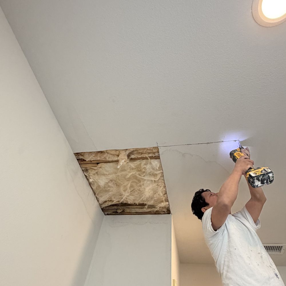 contractor using drill to repair ceiling drywall after ice dam water damage