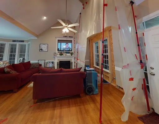 plastic containment sheeting and air mover set up inside living room after water damage